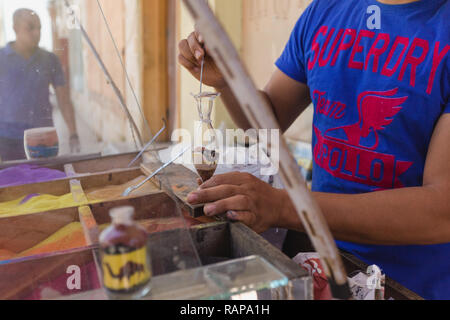 SHARM EL SHEIKH, Egitto - 16 Maggio 2018: Closeup vista di uomo adulto rendendo souvenir da colorato Sabbia decorativa all'aperto per la vendita ai turisti. Foto Stock