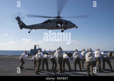 Mar Cinese Orientale (feb. 28, 2017) Marines assegnato a combattere Cargo ricevere pallet di alimentazione da un MH-60S Sea Hawk, assegnato al mare in elicottero Combat Squadron (HSC) 25, sul ponte di volo di assalto anfibio nave USS Bonhomme Richard (LHD 6) durante un rifornimento in mare (RAS) con l'Henry J. Kaiser-classe oliatore di rifornimento USNS Pecos (T-AO 197). Bonhomme Richard è su una pattuglia di routine, operando in Indo-Asia-regione del Pacifico per servire come un forward-capacità per qualsiasi tipo di emergenza. Foto Stock