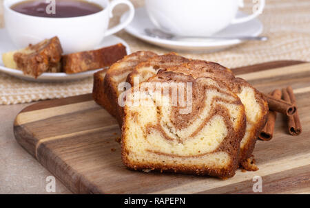 Primo piano di una fila di fette di cannella swirl pane su un tagliere con tazze da caffè in background Foto Stock