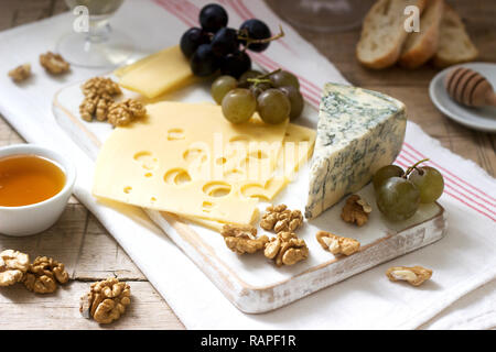 Antipasti di vari tipi di formaggio, uva, noci e miele, servita con vino bianco e rosso. Stile rustico. Foto Stock