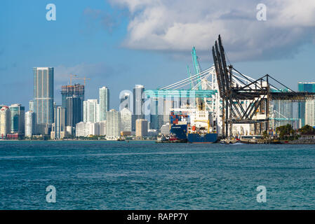 Miami Beach, Florida - Vista del Porto di Miami con grandi navi container e gru. Sullo sfondo i grattacieli di lo skyline del centro cittadino. Foto Stock
