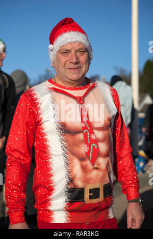 Uomo in costume al primo giorno del nuovo anno nuotare a Rhu Marina, Argyll, Scozia. Foto Stock