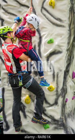 Istruttore maschio lavora con un giovane ragazzo sulla parete di arrampicata Foto Stock