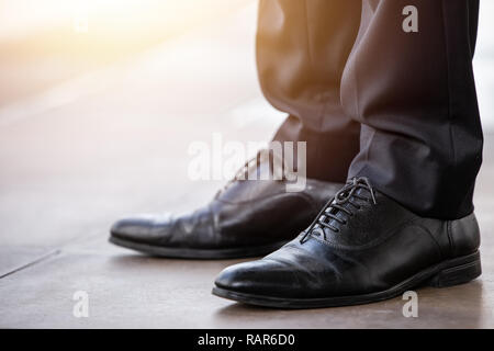 Imprenditore closeup scarpe in pelle di colore nero nuovo pulito permanente lucido pronti a camminare. Foto Stock