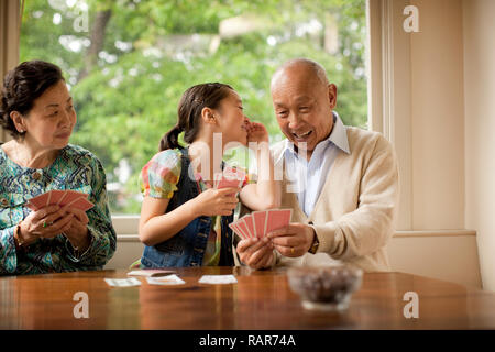 Coppia senior giocando a carte con loro nipote. Foto Stock