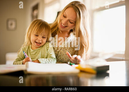 Giovane ragazza che gioca con un libro da colorare con sua madre. Foto Stock