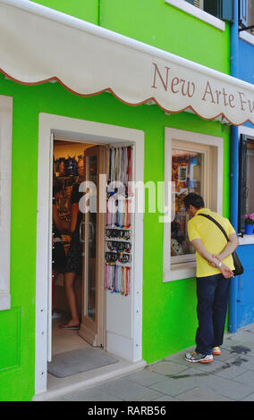 Un turista cerca nella vetrina di un negozio sulla isola veneziana di Burano. Foto Stock