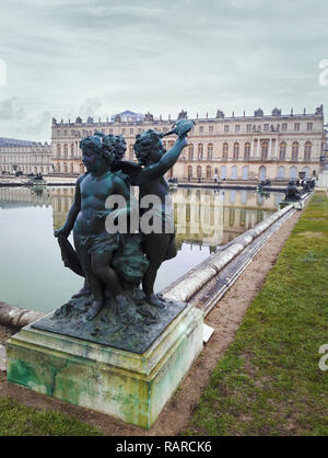 Chateau Versailles vista castello dal giardino di sculture di tre bambini rilasciare un piccione vicino alla fontana. Foto Stock