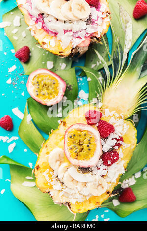 Gustoso frullato di appetitosi bocce servita in metà ananas decorato con taglio frutto della passione, scaglie di noce di cocco e semi di chia.la vita sana pulire mangiare co Foto Stock