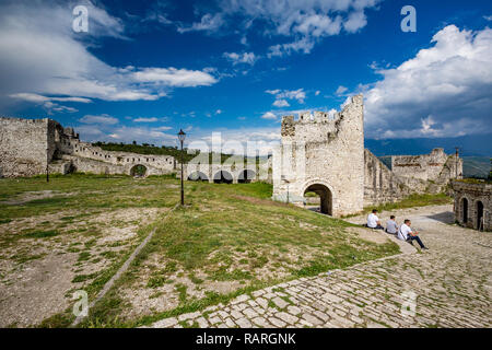 BERAT, ALBANIA - 17 Maggio 2017: tre uomini siedono in pietra antica strada tra le rovine della vecchia città medievale sulla cima delle colline soleggiate guerra Foto Stock