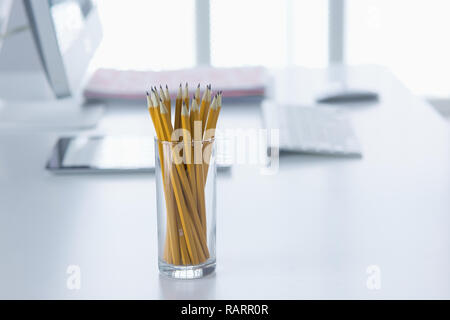 Matite di grafite in un bicchiere di vetro sul tavolo per ufficio. Concetto. Foto Stock