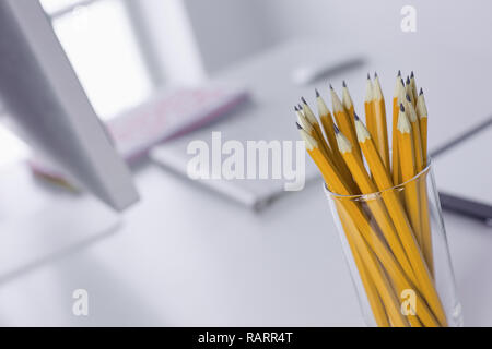 Matite di grafite in un bicchiere di vetro sul tavolo per ufficio. Concetto. Foto Stock