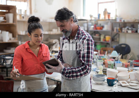 Maschio e femmina potter discutendo su tablet pc Foto Stock