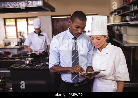 Manager maschio e femmina chef usando tavoletta digitale in cucina Foto Stock