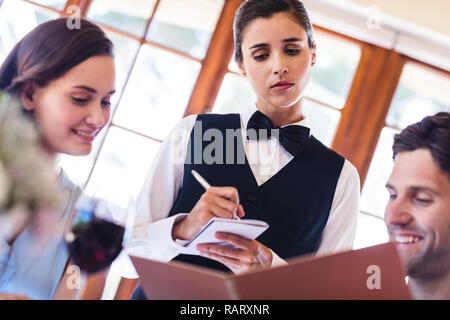 Cameriera prendendo un ordine da un giovane Foto Stock