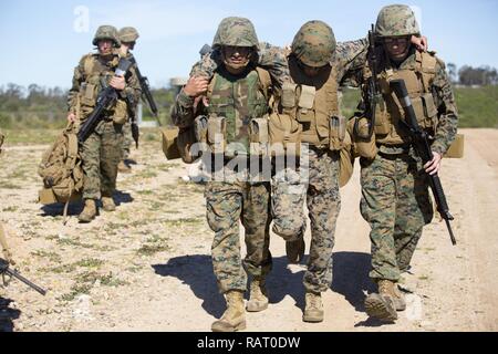 Stati Uniti Marine Corps Sgt. Carlos Ortiz, sinistra, e Lance Cpl. Adam J. Simpson, destra, con banda di Marino San Diego, società di servizio (SVCO), sede centrale e servizio battaglione (HQSVCBN), eseguire Cpl. Il Thanh T. Nguyen, un impiegato di magazzino con assunzione di abbigliamento, SVCO, HQSVCBN, al Marine Corps Air Station Miramar, California, 15 febbraio, 2017. Ortiz e Simpson scortato Nguyen per la sicurezza come parte di un campo simulato procedura di cura durante un servizio Società Super Squad la concorrenza. Foto Stock