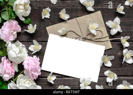 Schermata bianca vuota biglietto di auguri con rosa e rose bianche nella cornice di fiori di gelsomino su tavola in legno rustico. flat laici. vista superiore Foto Stock