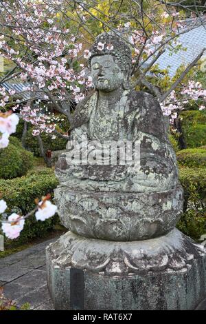 Kyoto, Giappone - statua di Buddha - antica scultura in pietra e fiori di ciliegio fiori a Ninna-ji. Foto Stock