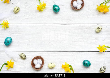 Telaio di pasqua a base di uova e di fiori di primavera in bianco sullo sfondo di legno. Composizione di pasqua. vista superiore con spazio di copia Foto Stock