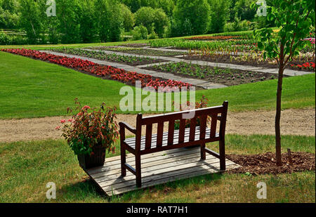 Un paesaggio orizzontale immagine con un vuoto di sedile posteriore che si affaccia su un'area thats con fiori nei giardini Devoniano vicino a Edmonton Alberta. Foto Stock