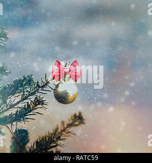 Natale oro Sfera decorativa appesi da pino ramo con la neve sullo sfondo. Immagine di stock. Foto Stock