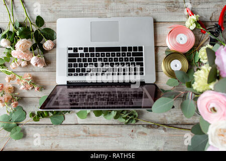 Close-up della tastiera portatile e tavola floreale. La donna blogger e creatori di contenuti di social network e blog negozio di fiori. Il concetto di negozio online e di consegna floreale. SMM promozione Foto Stock