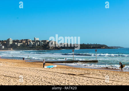 Mattina haze a Manly Beach con surfers la preparazione per le onde su un blu perfetto giorno di estate in un suggestivo scenario (Sydney, Australia) Foto Stock