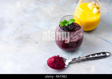 Colorati frullati di frutta con acai polvere sul tavolo Foto Stock