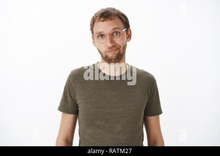 Ritratto di carino e disponibile bella amico maschio in bicchieri e verde t-shirt casual sorridente cordiale alla fotocamera in piedi rilassato e tranquillo su sfondo bianco avente una normale conversazione Foto Stock