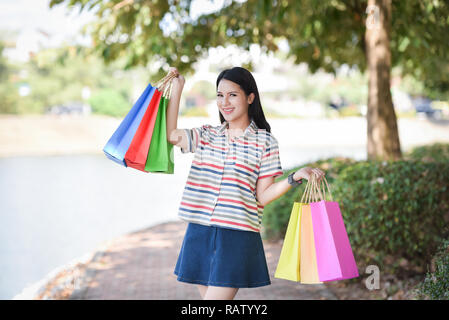 Giovane donna shopping esterno / lady donna felice sorridente e tenendo colorati negozi sacchetto in mano sul luminoso giorno - Ritratto di belle ragazze shopping Foto Stock