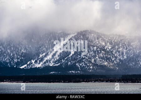 Nuvole temporalesche che copre la Sierra Mountains, il litorale del Lago di Tahoe visibile in primo piano Foto Stock