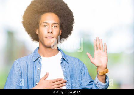 Giovane americano africano uomo con capelli afro giuramento con la mano sul petto e aprire Palm, facendo una promessa di fedeltà giurata Foto Stock