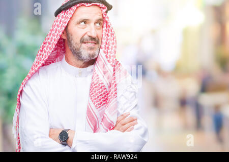 Senior uomo arabo indossando keffiyeh su sfondo isolato sorridente cercando lato e lo sguardo lontano pensando. Foto Stock