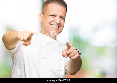 La mezza età uomo arabo wearig t-shirt bianco su sfondo isolato rivolti a voi e la fotocamera con le dita, sorridente positiva e allegra Foto Stock