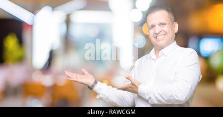 Età media arabi uomo elegante su sfondo isolato invitante per immettere sorridente naturale con mano aperta Foto Stock