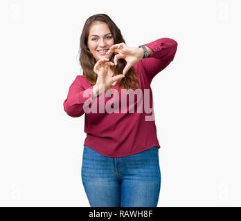 Bella la dimensione più giovane donna su sfondo isolato sorridente in amore che mostra il simbolo del cuore e la forma con le mani. Concetto romantico. Foto Stock