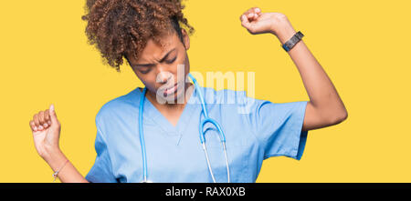 Giovane africano medico americano donna sullo sfondo isolato Stretching schiena, stanco e rilassato, assonnato e sbadigli per la mattina presto Foto Stock