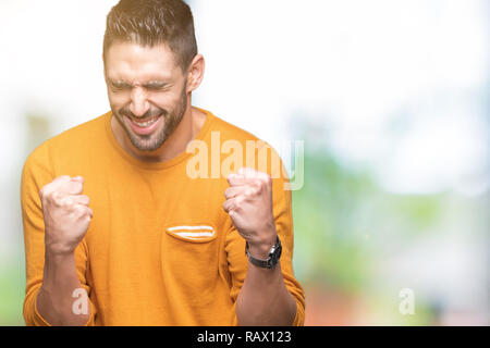 Giovane uomo bello su sfondo isolato molto felici ed eccitati facendo vincitore gesto con le braccia sollevate, sorridente e urlando per il successo. Celebrati Foto Stock