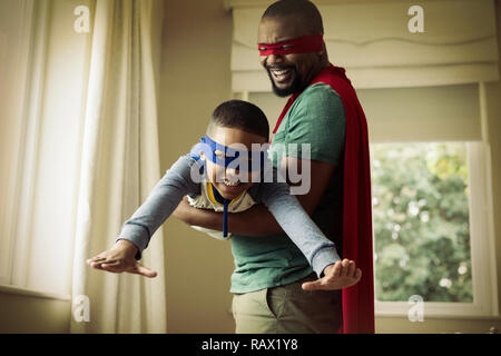 Il figlio e il padre fingendo di essere un supereroe a casa Foto Stock