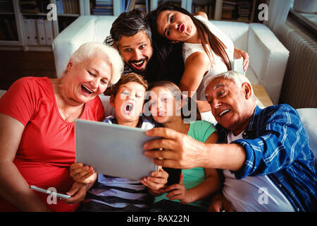 Multi generazione famiglia prendendo un selfie sulla tavoletta digitale in salotto Foto Stock