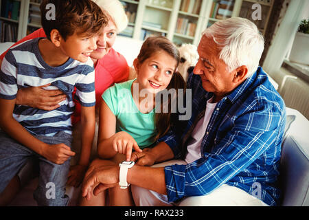 Nonni e nipoti guardando smartwatch in salotto Foto Stock