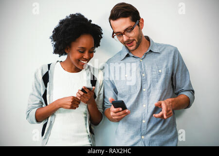 Uomo e donna che utilizza il telefono cellulare Foto Stock