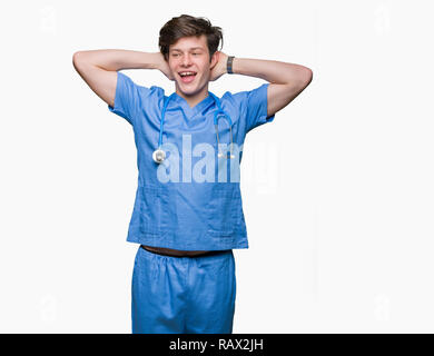 Giovane medico medico che indossano uniformi su sfondo isolato rilassante e stretching con le braccia e le mani dietro la testa ed il collo, sorridendo felice Foto Stock