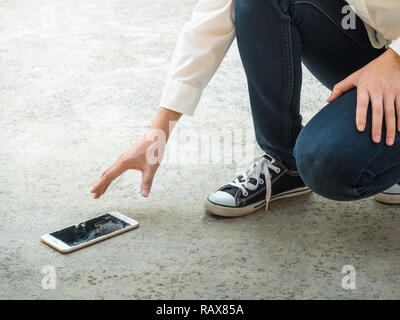 Persona Picking rotto Smart Phone (schermo incrinato) della Terra Foto Stock