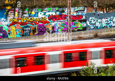 Graffiti dipinti su un muro di cemento a una ferrovia via nei pressi della stazione centrale, con il treno veloce, Germania, Essen, Foto Stock