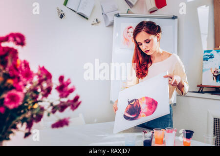 I capelli rossi ricci disegno artista dipinge sulla sua pittura in marmo Foto Stock