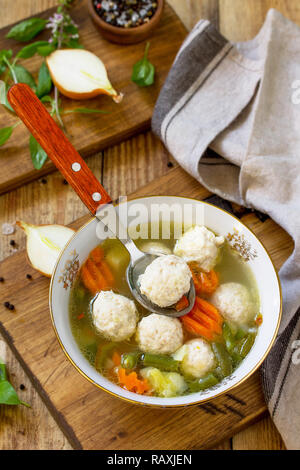 Il concetto menù dietetici. Una sana zuppa di verdure e polpette di pollo in una ciotola sul tavolo in legno in stile rustico. Foto Stock