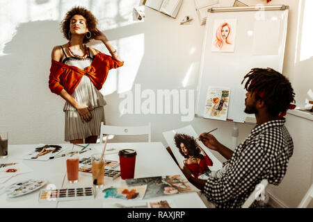 Curly donna che indossa abiti corti e accessori in posa per ritratto Foto Stock