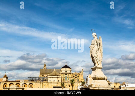 Vista della Mezquita, Catedral de Cordoba dietro un angelo statua sul ponte romano. Un ex moschea moresca che è ora la cattedrale di Cordoba, Mezqui Foto Stock