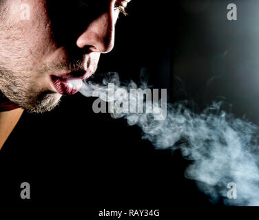 parte di mans faccia che soffia fumo di sigaretta dalla sua bocca Foto Stock